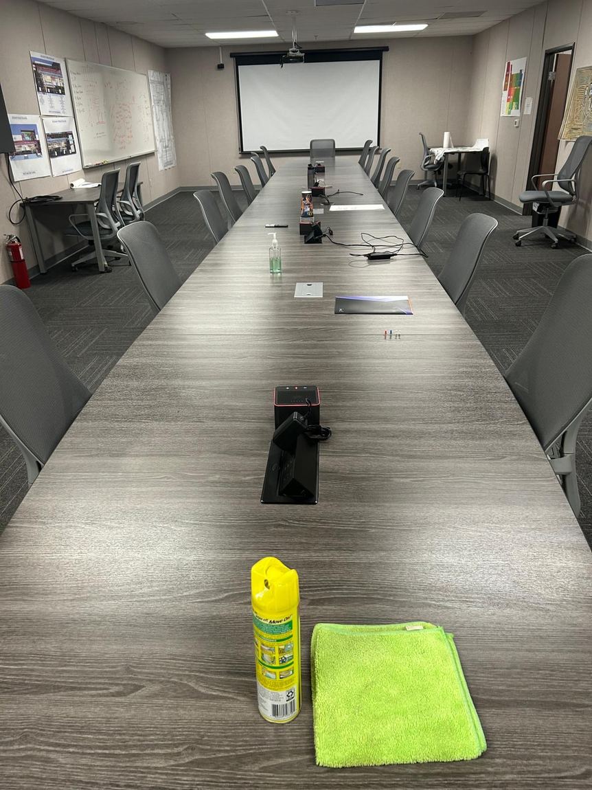 A long conference table wiped down, with a microfiber cloth and polish left at the near end