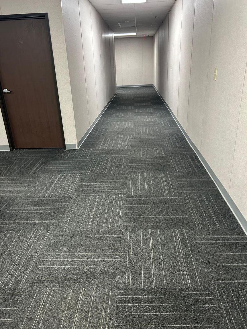 A freshly vacuumed office hallway with clean carpet tiles