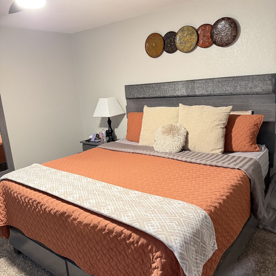 A bedroom with the bed made, pillows arranged and both nightstands clear