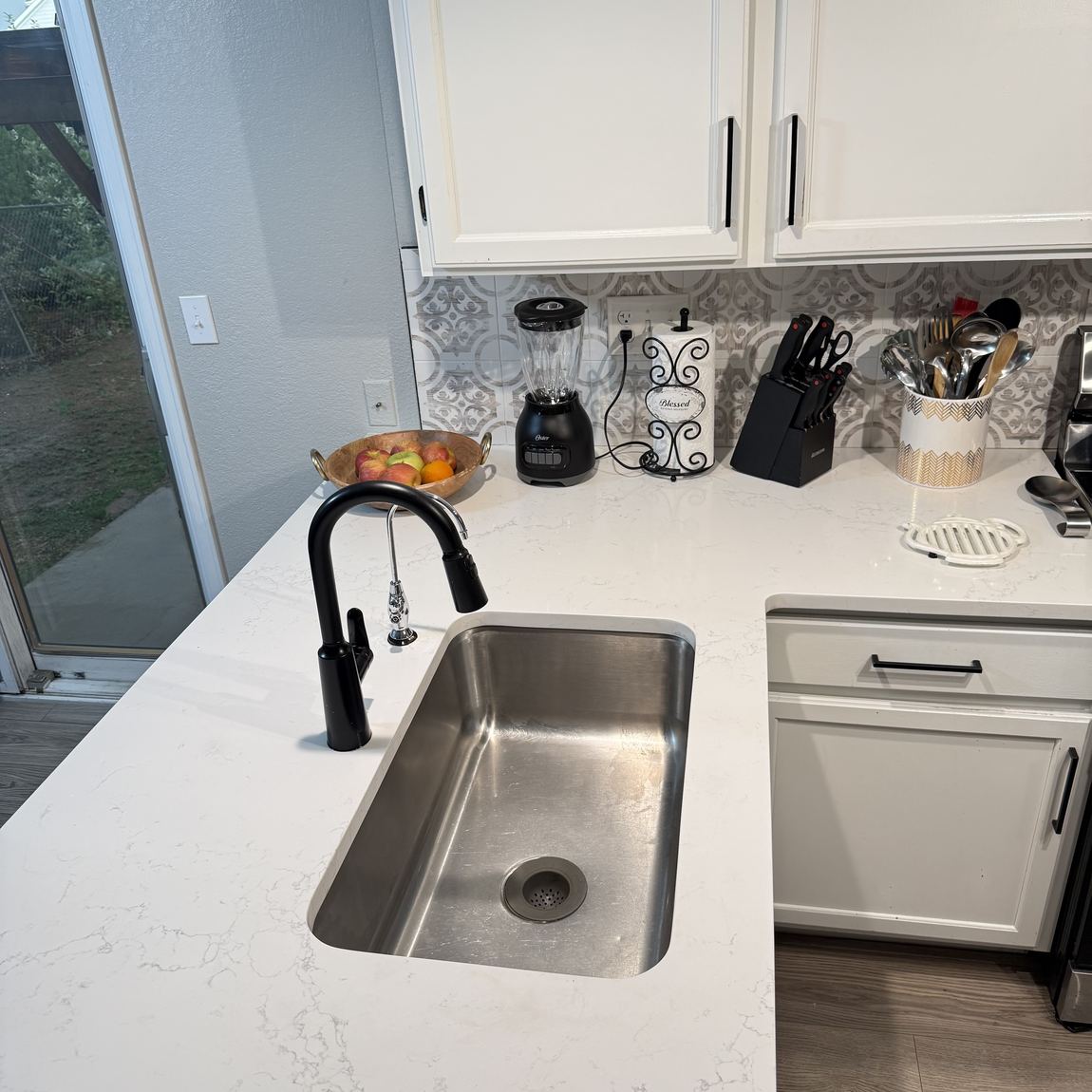 A kitchen counter wiped clear with a clean sink and backsplash