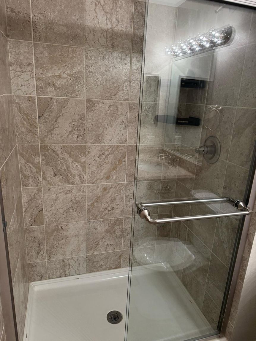 A tiled shower cleaned, with clear glass and no water spots