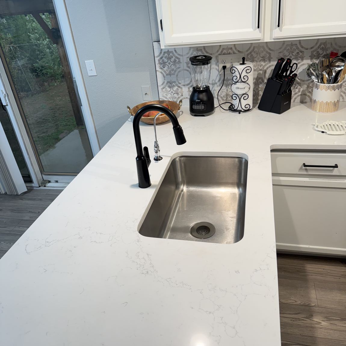 An empty stainless steel kitchen sink, dry and clean, with clear counter around it